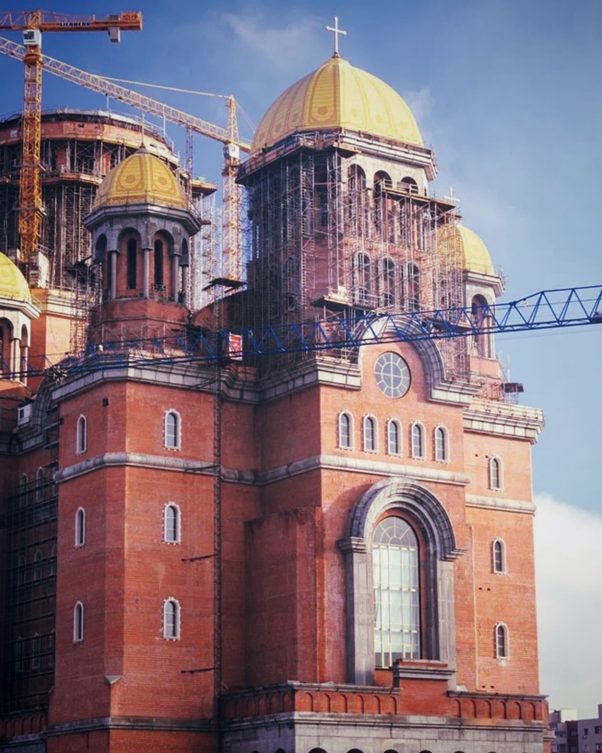 The National Cathedral in Bucharest under construction, its gilded domes and brick towers ringed by cranes and scaffolding, coordinated on site by the CRV Management team from 2010 to 2019