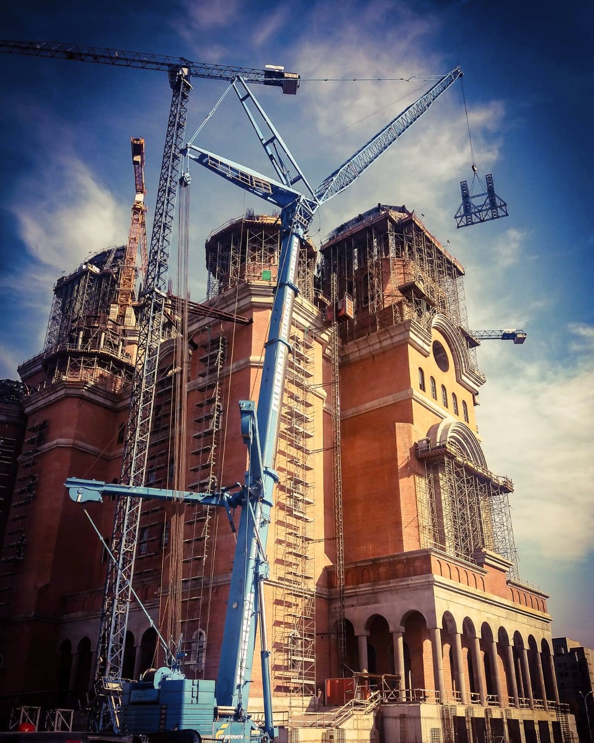 The National Cathedral in Bucharest under construction, surrounded by tower cranes and scaffolding