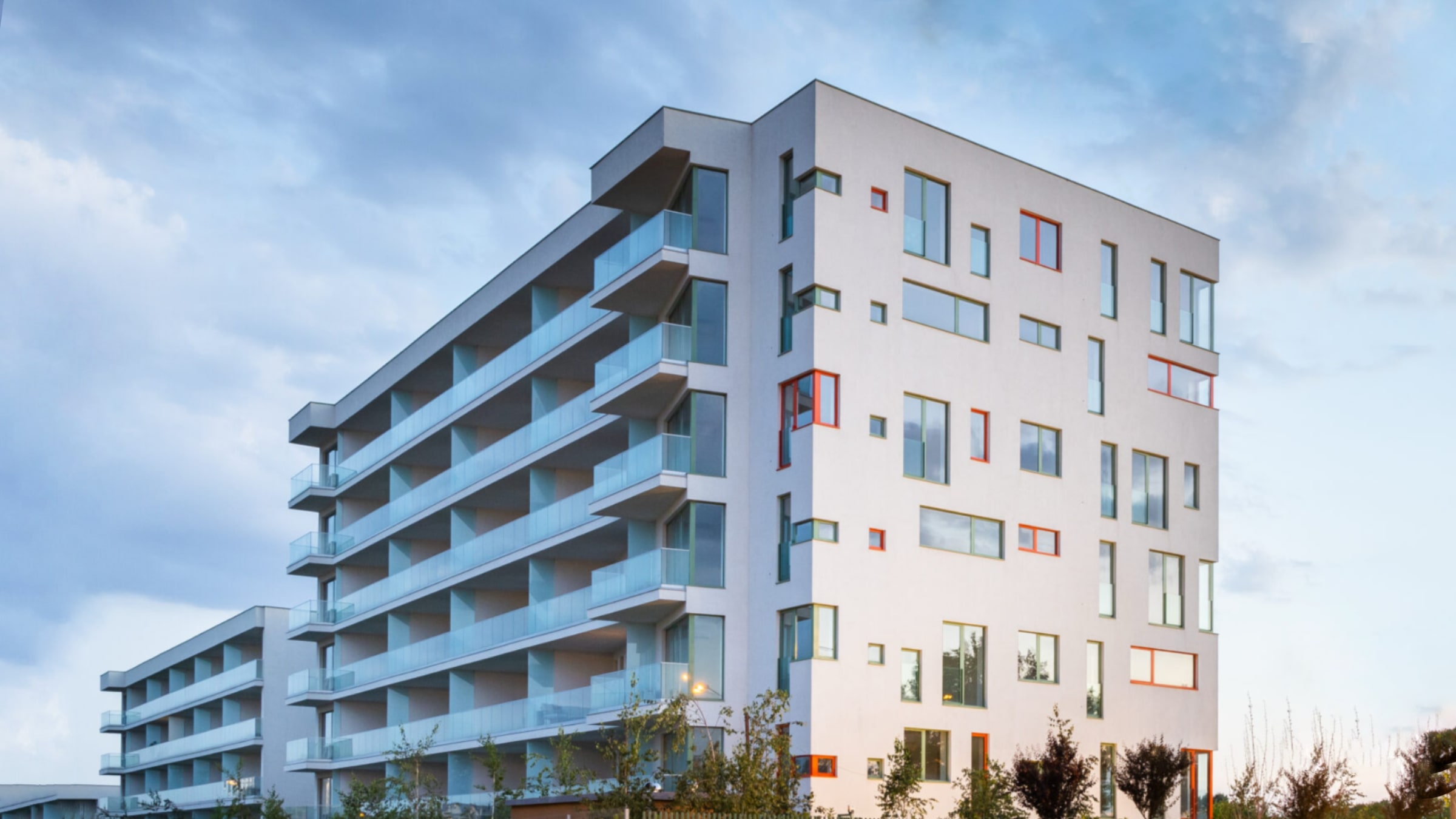 A completed modern residential apartment building with balconies at dusk