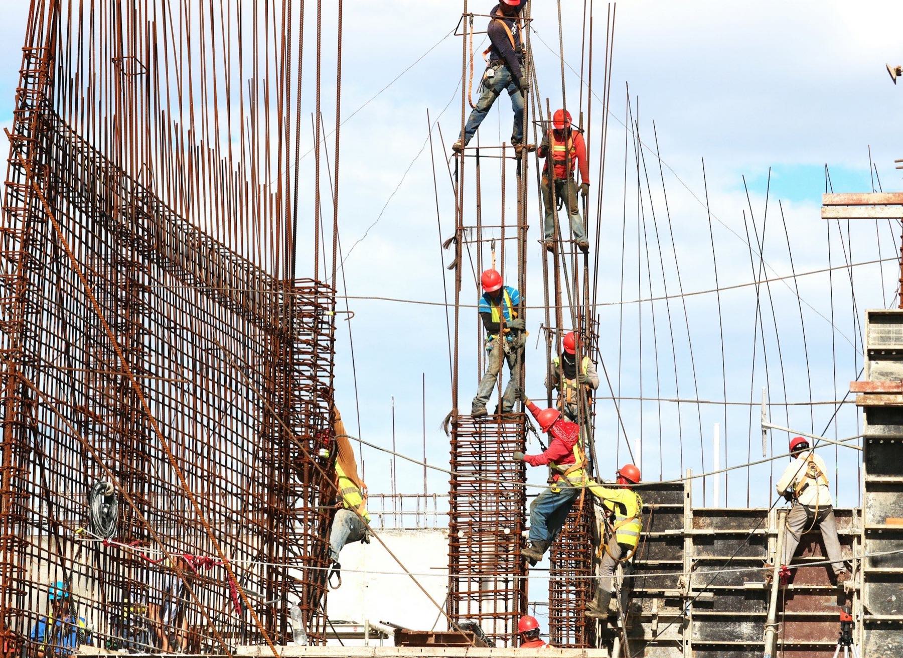 A construction crew working on a reinforced-concrete structure against the sky